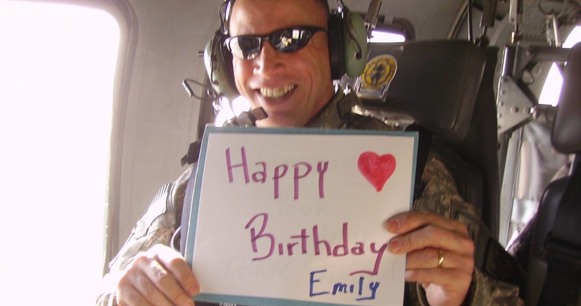 Ed Rothstein holding happy birthday sign while deployed
