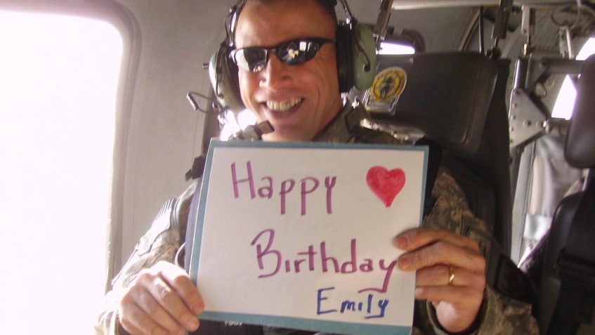 Ed Rothstein holding happy birthday sign while deployed